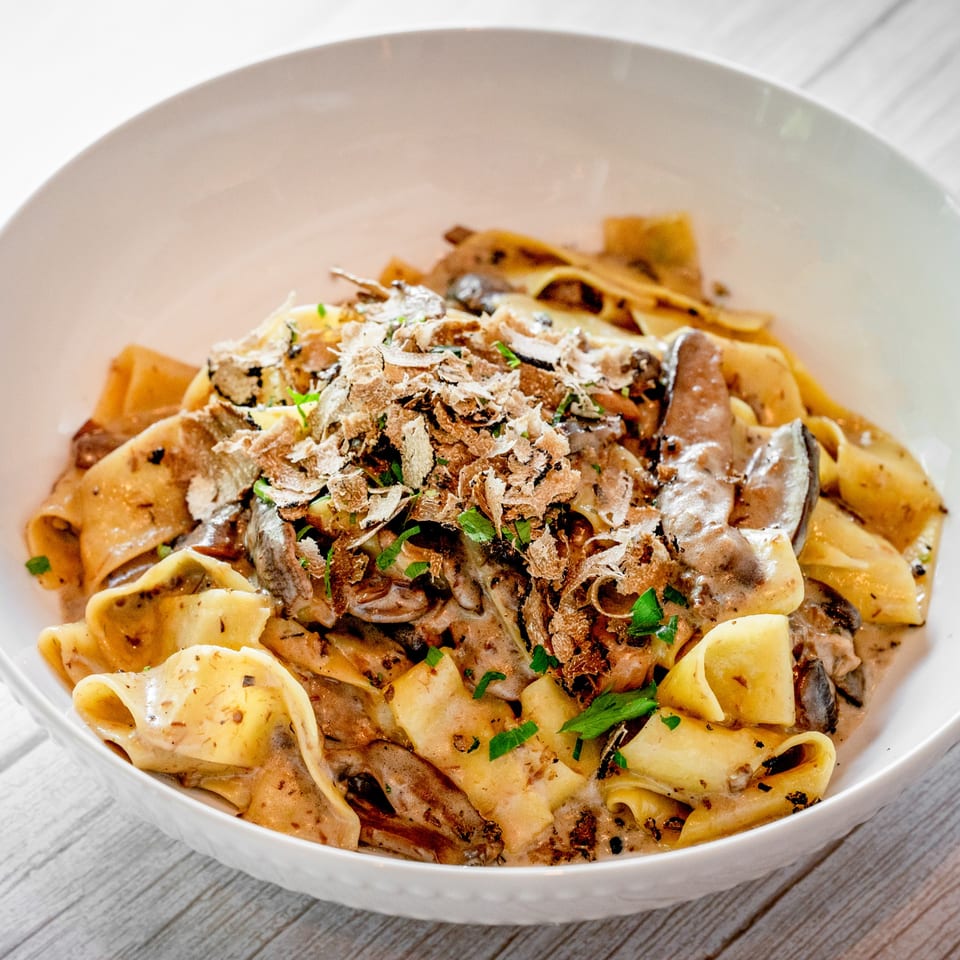 Close-up of Tartufo Restaurant's pappardelle pasta with creamy mushroom sauce, shaved truffles, and parsley.