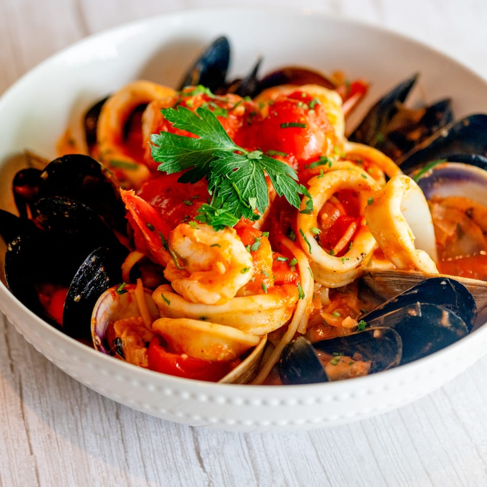 Close-up of Tartufo Restaurant's Italian seafood pasta with mussels, shrimp, and calamari in red sauce.