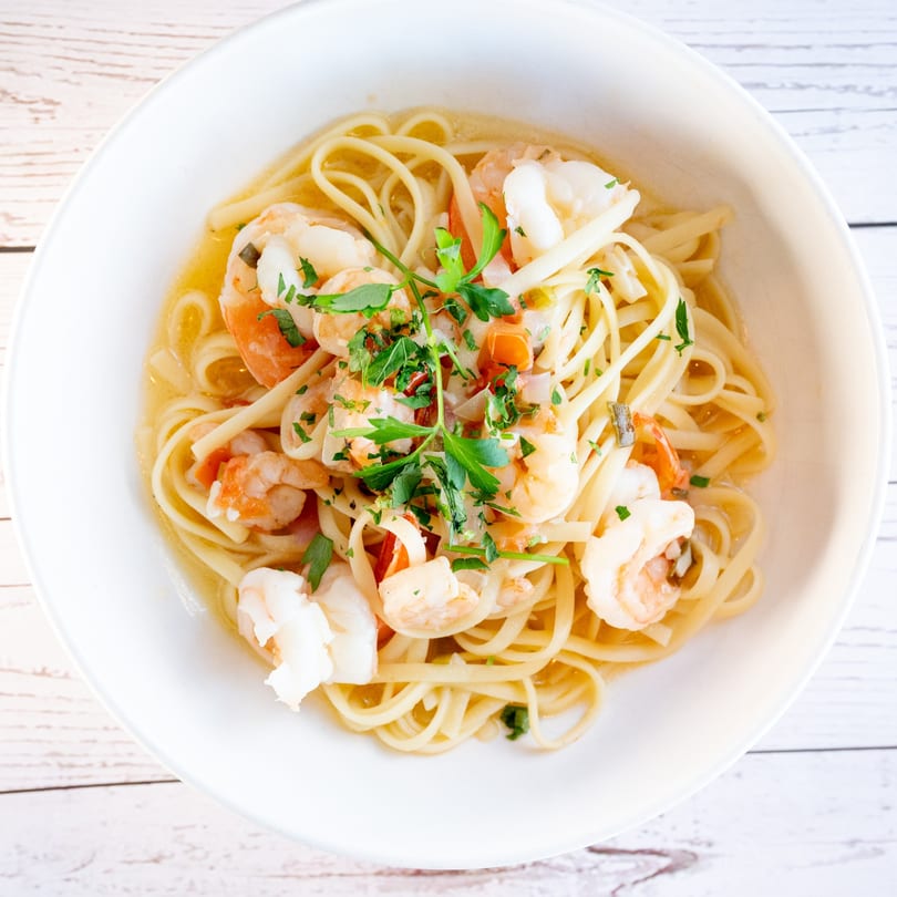 Tartufo Restaurant's shrimp scampi with linguine, garlic, and parsley in a white bowl.
