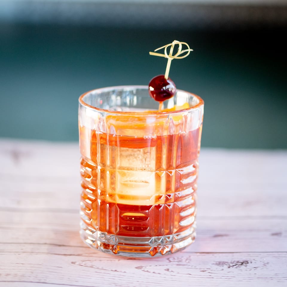 A classic Italian cocktail, likely an Old Fashioned, garnished with an orange slice and cherry.